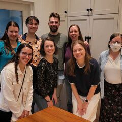 A group of smiling people standing around a table