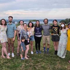 A group of smiling people standing outside on a grassy field